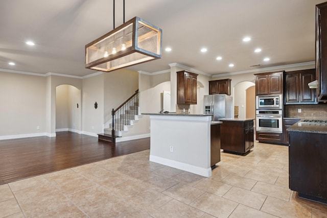 kitchen featuring stainless steel appliances, arched walkways, ornamental molding, and decorative backsplash