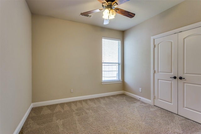 unfurnished bedroom featuring light colored carpet, a ceiling fan, baseboards, visible vents, and a closet