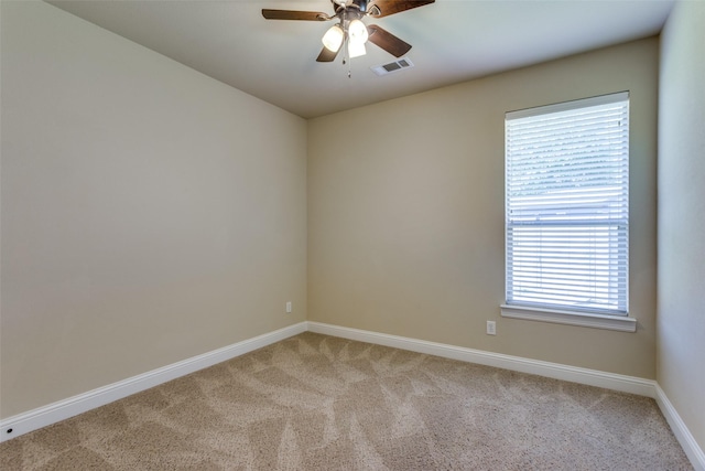 empty room with a ceiling fan, light colored carpet, visible vents, and baseboards