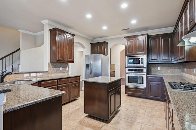 kitchen with dark brown cabinetry, arched walkways, visible vents, stainless steel appliances, and a sink