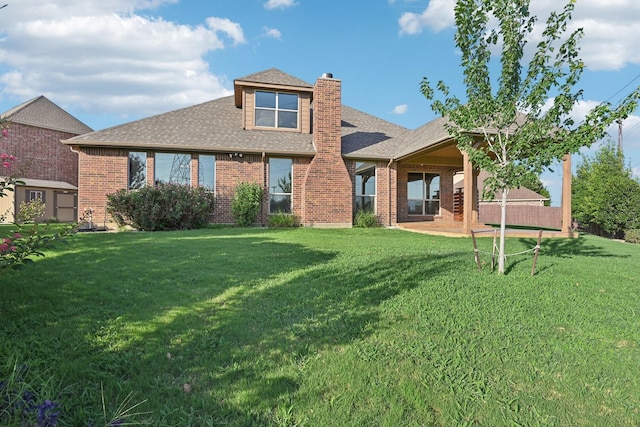 rear view of house featuring brick siding, a shingled roof, a chimney, and a lawn