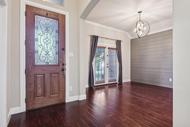 entrance foyer featuring baseboards, arched walkways, ornamental molding, wood finished floors, and an inviting chandelier