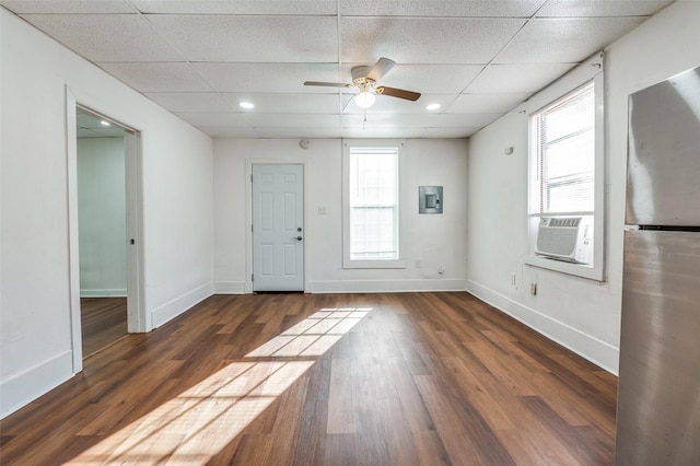 empty room featuring a healthy amount of sunlight, cooling unit, a drop ceiling, and wood finished floors