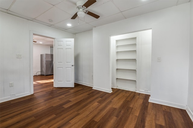 unfurnished bedroom featuring baseboards, ceiling fan, wood finished floors, freestanding refrigerator, and a spacious closet