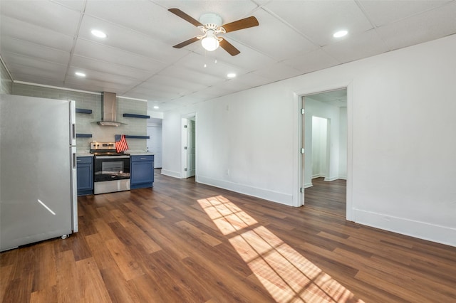 kitchen with dark wood-style floors, light countertops, appliances with stainless steel finishes, blue cabinets, and wall chimney exhaust hood