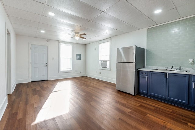 kitchen with a sink, light countertops, blue cabinetry, freestanding refrigerator, and dark wood finished floors