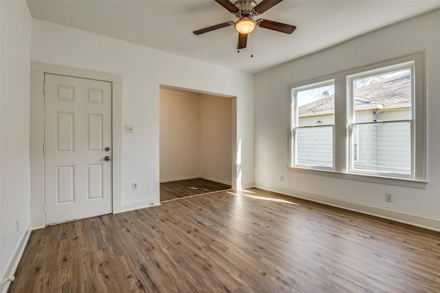 empty room featuring a ceiling fan, baseboards, and wood finished floors