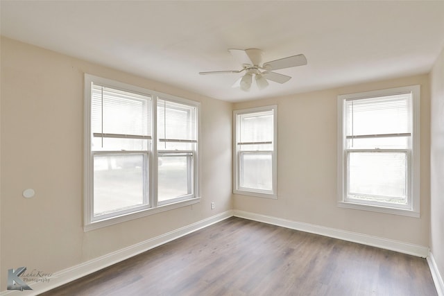 unfurnished room with dark wood-style floors, a healthy amount of sunlight, and baseboards