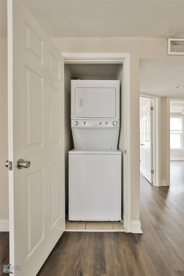 laundry area featuring visible vents, laundry area, dark wood-style floors, and stacked washer and clothes dryer