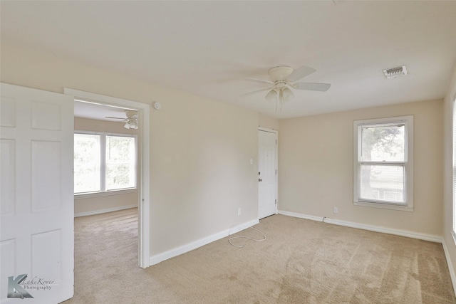 unfurnished room with a ceiling fan, light carpet, visible vents, and baseboards