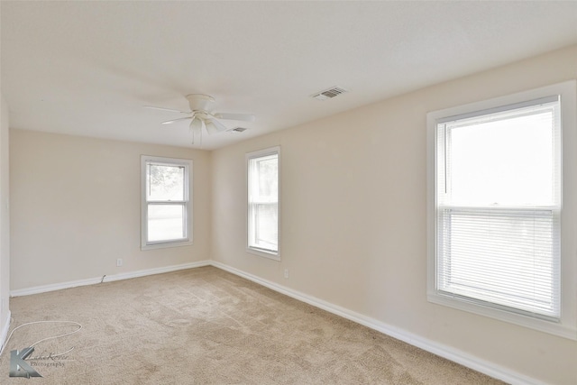 carpeted spare room featuring a ceiling fan, visible vents, and baseboards