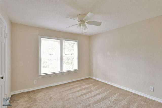 spare room featuring a ceiling fan, carpet, and baseboards