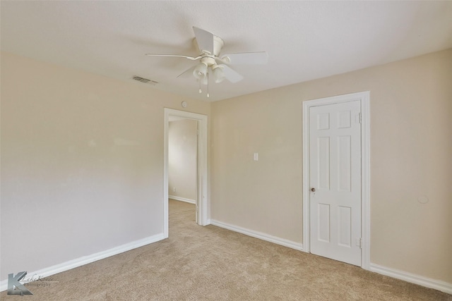 unfurnished room with baseboards, ceiling fan, visible vents, and light colored carpet