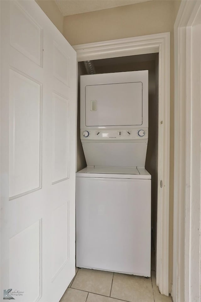 laundry area featuring laundry area, light tile patterned floors, and stacked washer and clothes dryer