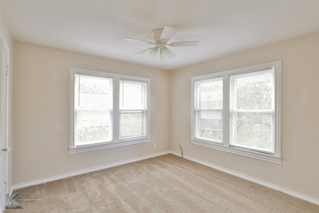 unfurnished room with baseboards, a ceiling fan, and light colored carpet