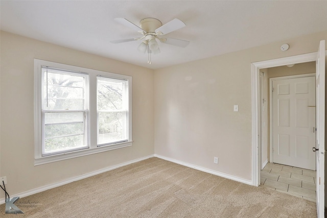 unfurnished room with light carpet, ceiling fan, baseboards, and light tile patterned floors