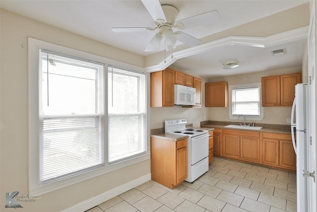 kitchen featuring brown cabinets, visible vents, a sink, white appliances, and baseboards