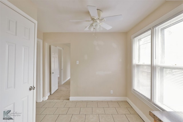 empty room featuring light tile patterned flooring, ceiling fan, and baseboards