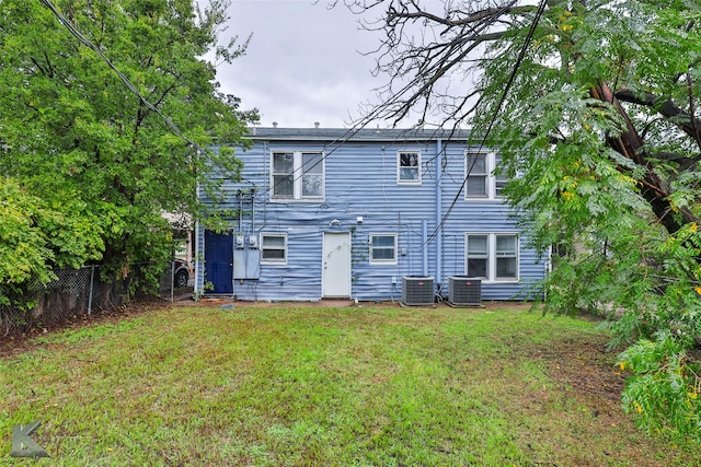 rear view of house with a yard, fence, and central air condition unit