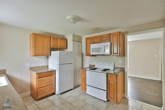 kitchen featuring light countertops, white appliances, light tile patterned flooring, and baseboards