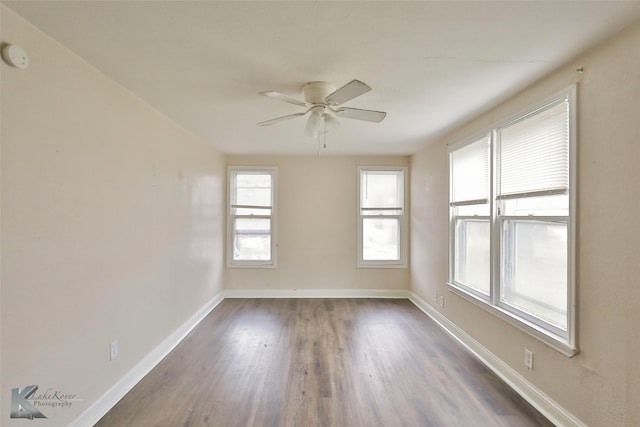 empty room featuring dark wood-style flooring, ceiling fan, and baseboards