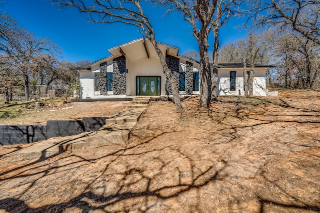 rear view of house with stone siding and fence