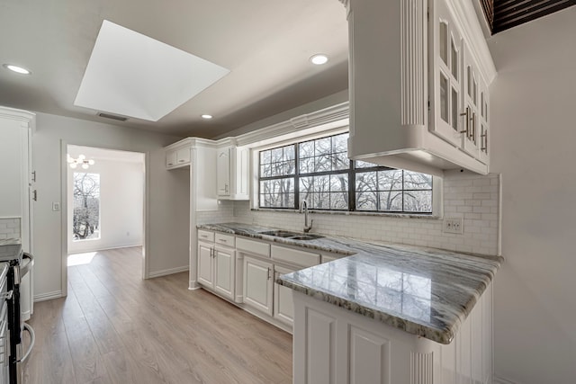 kitchen with light wood-style flooring, a sink, visible vents, and white cabinetry