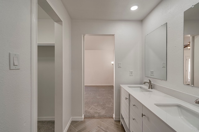 full bathroom with double vanity, baseboards, and a sink