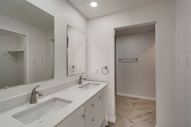 full bath featuring double vanity, wood finish floors, a sink, and recessed lighting