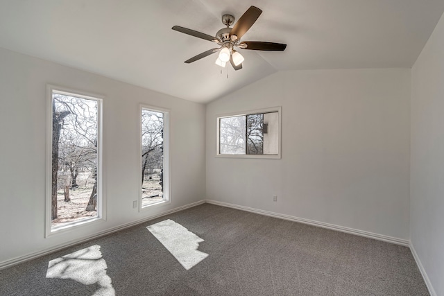 spare room with lofted ceiling, dark carpet, baseboards, and a healthy amount of sunlight