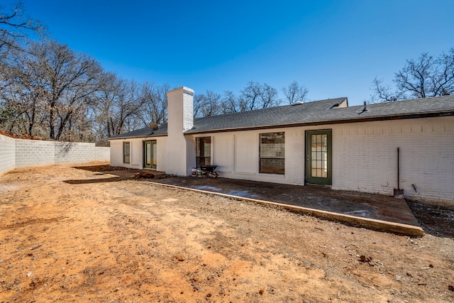 back of house featuring french doors, brick siding, a chimney, a patio area, and fence