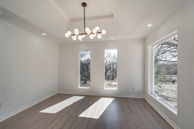 unfurnished dining area featuring dark wood-style flooring, recessed lighting, a raised ceiling, and baseboards