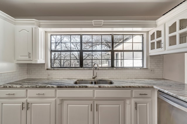 kitchen featuring decorative backsplash, dishwasher, white cabinets, glass insert cabinets, and a sink