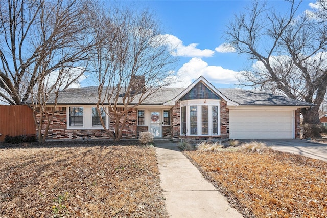 view of front of house featuring a garage, concrete driveway, brick siding, and fence