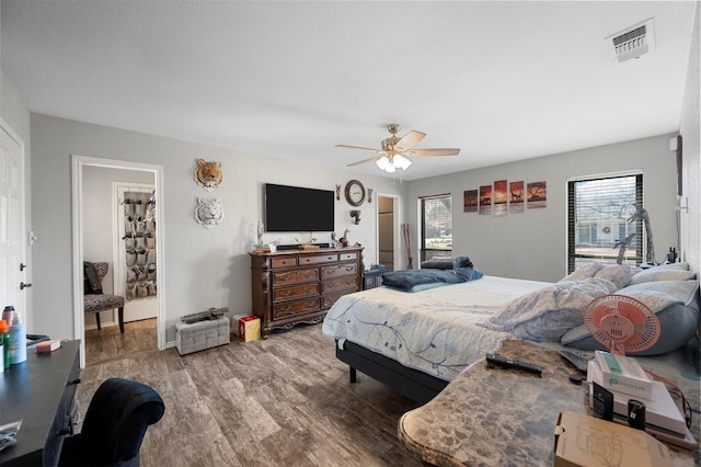 bedroom featuring a ceiling fan, visible vents, and wood finished floors