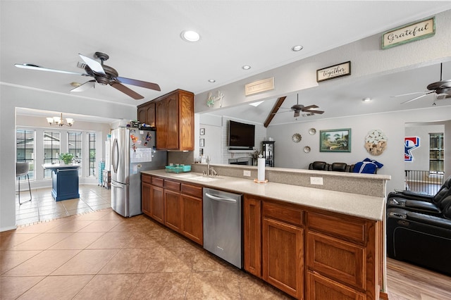 kitchen with appliances with stainless steel finishes, open floor plan, a peninsula, light countertops, and a sink