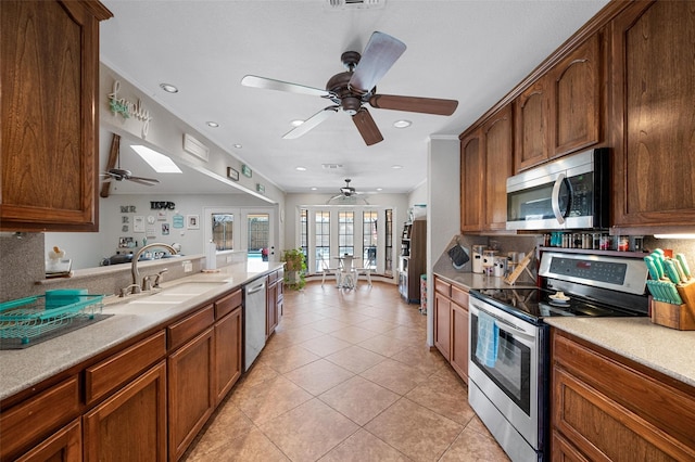 kitchen with light tile patterned floors, appliances with stainless steel finishes, backsplash, and a sink