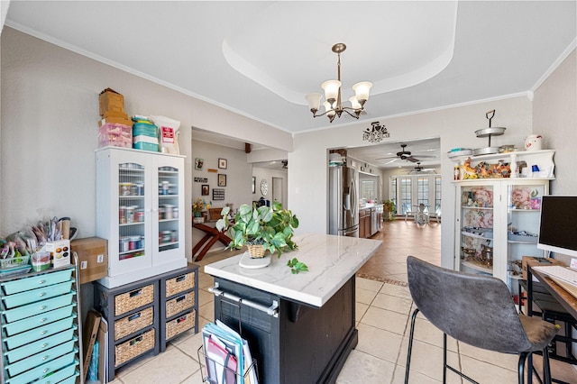 kitchen featuring light tile patterned floors, stainless steel fridge, a raised ceiling, ornamental molding, and hanging light fixtures