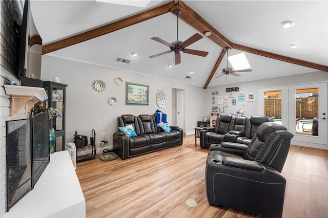 living room featuring a fireplace with raised hearth, light wood-style floors, visible vents, and vaulted ceiling with beams