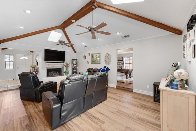 living area with lofted ceiling with beams, a brick fireplace, light wood-style flooring, and visible vents