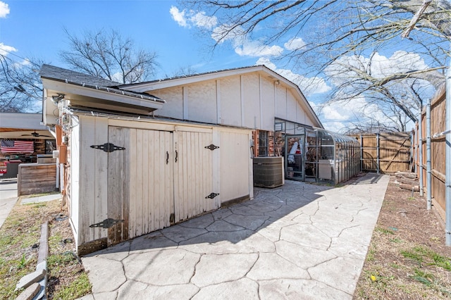 view of outdoor structure featuring fence, central AC unit, and an outdoor structure