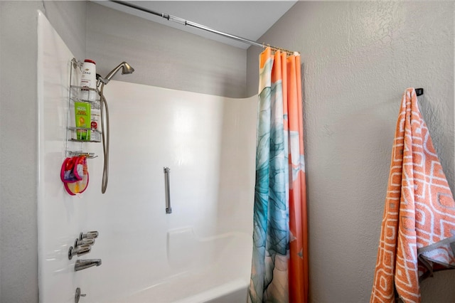 bathroom with a textured wall and shower / bathtub combination with curtain