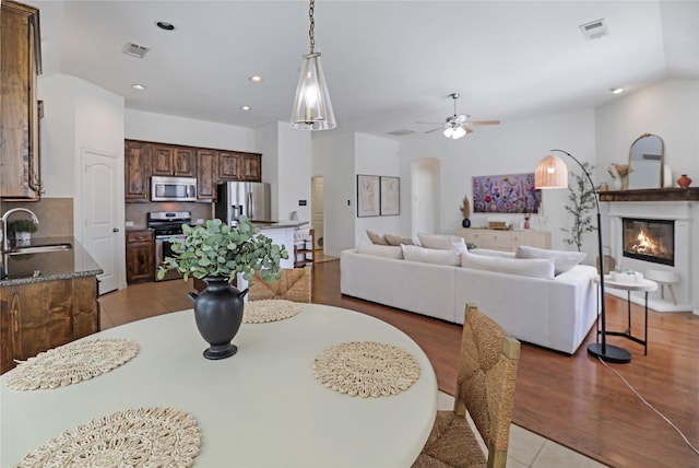 dining room with visible vents, a ceiling fan, a glass covered fireplace, light wood-style floors, and recessed lighting