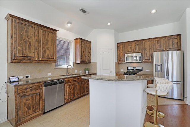 kitchen featuring light tile patterned flooring, stainless steel appliances, a sink, visible vents, and dark stone countertops