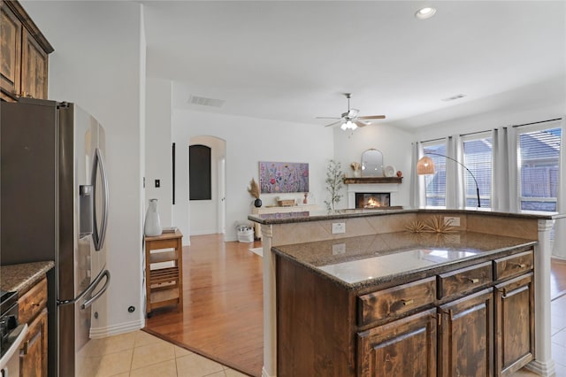 kitchen with a glass covered fireplace, visible vents, ceiling fan, and stainless steel refrigerator with ice dispenser