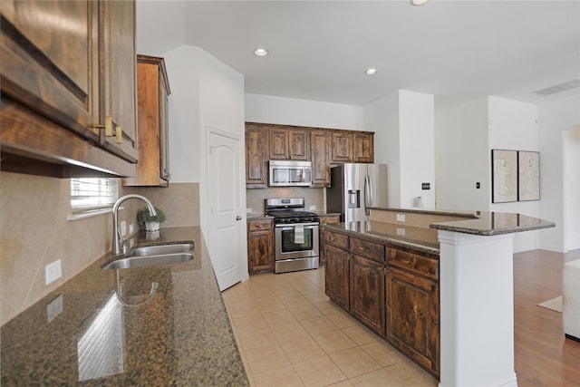 kitchen featuring visible vents, decorative backsplash, dark stone counters, stainless steel appliances, and a sink