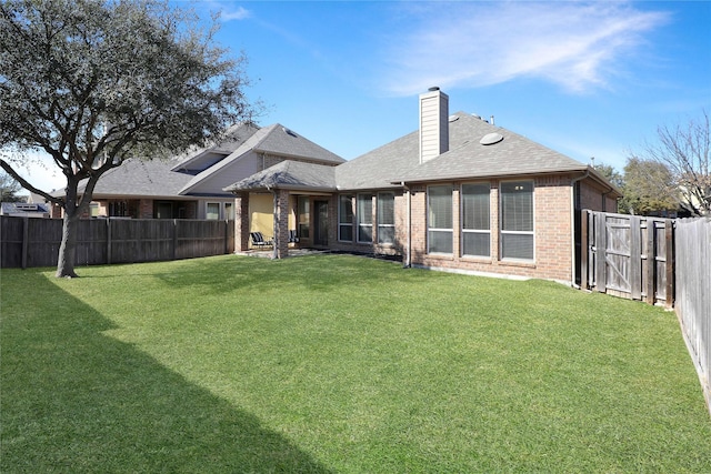 rear view of house featuring a chimney, fence, a lawn, and brick siding