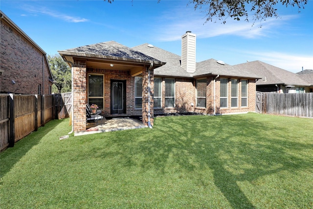 rear view of property featuring brick siding, a yard, and a fenced backyard