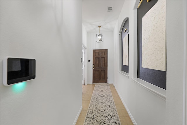 doorway to outside with baseboards, visible vents, and light tile patterned flooring