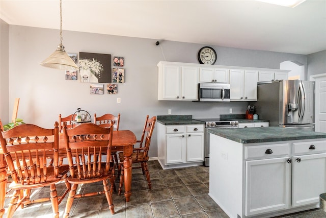 kitchen with stainless steel appliances, hanging light fixtures, dark countertops, and white cabinets